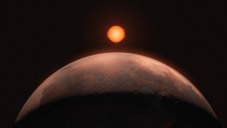 This artist's representation an exoplanet discovered orbiting the nearby red dward Barnard's star shows the curved edge of a red, rocky planet in the foreground, with a reddish-orange star just above the horizon in the distance.